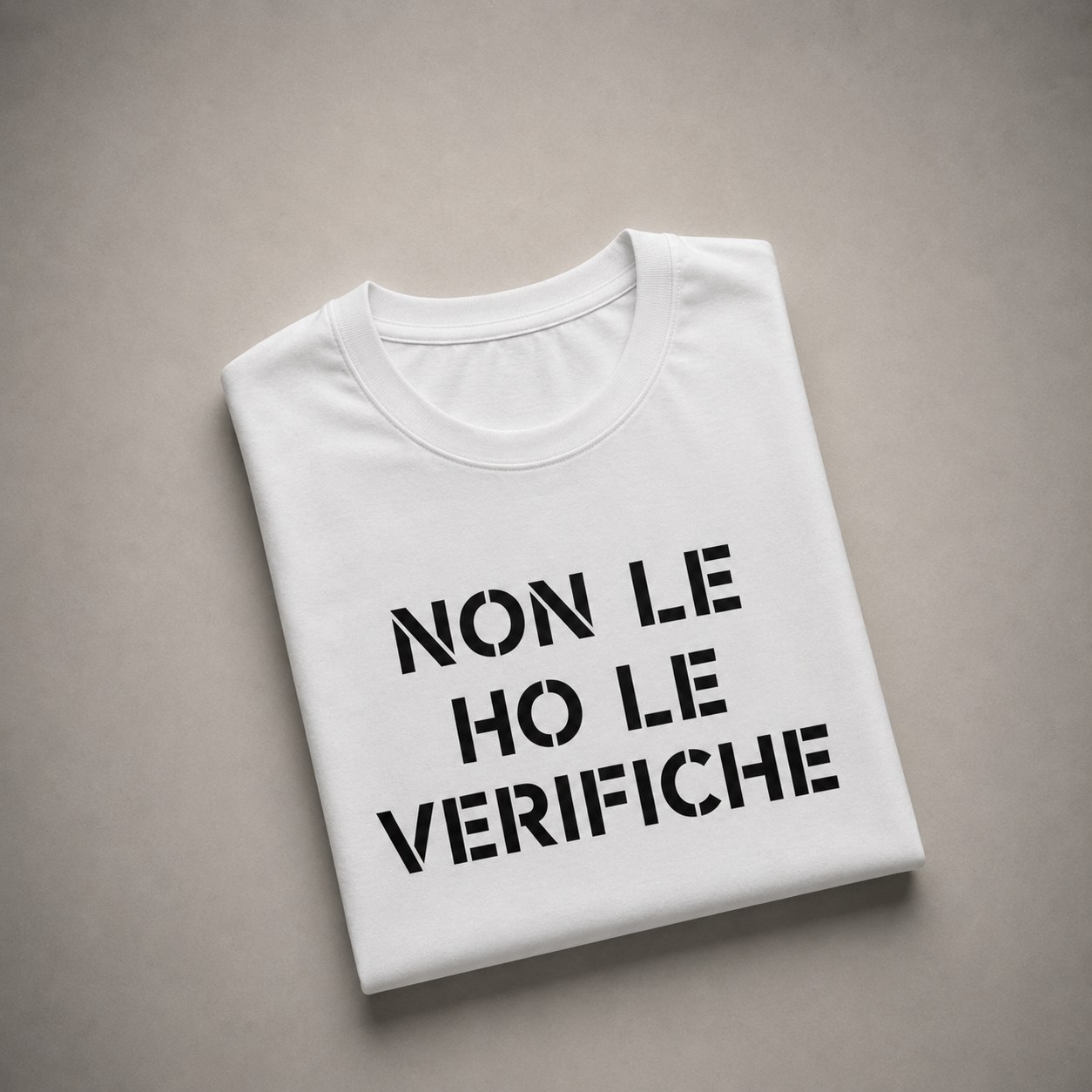 Maglietta bianca piegata con la scritta «Non le ho le verifiche», cotone 100%